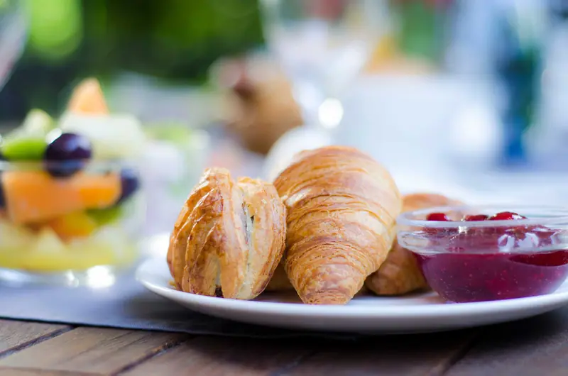 Croissants und frisches Obst auf einem Frühstücksteller (Symbolbild)
